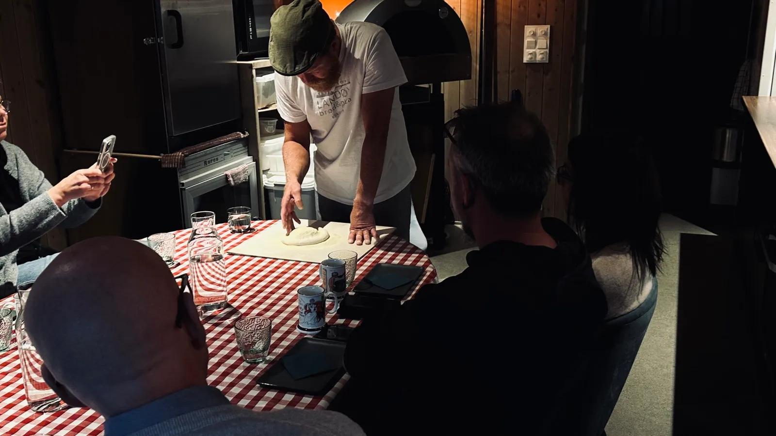 Pizzakurs hos Landøy Brød & Pizza – bakeren viser hvordan deigen formes for gjestene rundt den vedfyrte ovnen